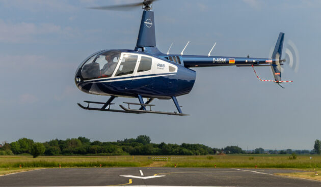 Heli-Flight-Time-Building Ein schwebender Helikopter über der Rollbahn